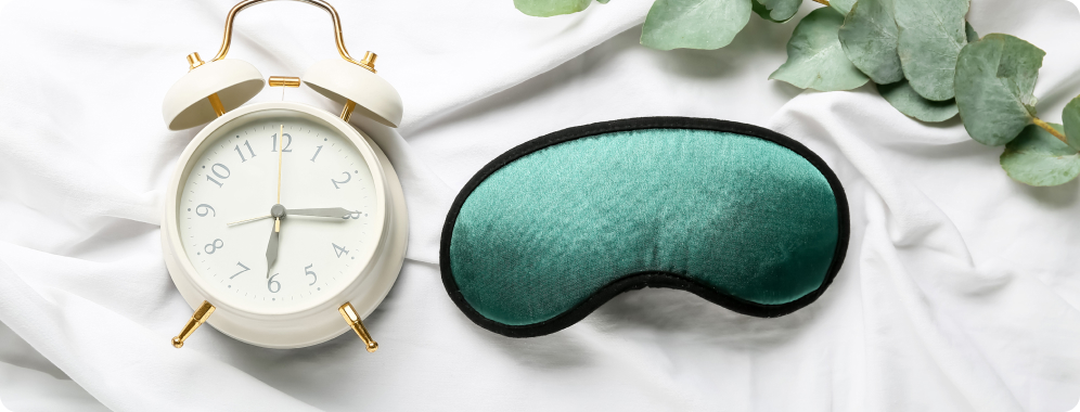 alarm clock and eye mask on bed