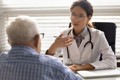 Young female doctor speaking to an older male patient