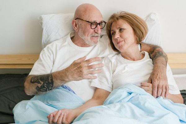 Elderly couple in bed sharing an intimate, affectionate moment. Captures warmth and love.