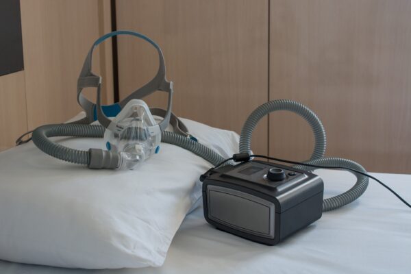 Cpap machine with a hose and cpap mask on top of a bed