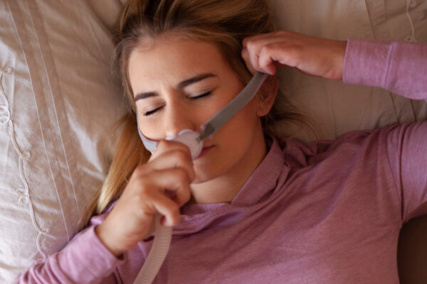 A woman adjusts her CPAP mask