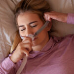 A woman adjusts her CPAP mask