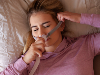 A woman adjusts her CPAP mask